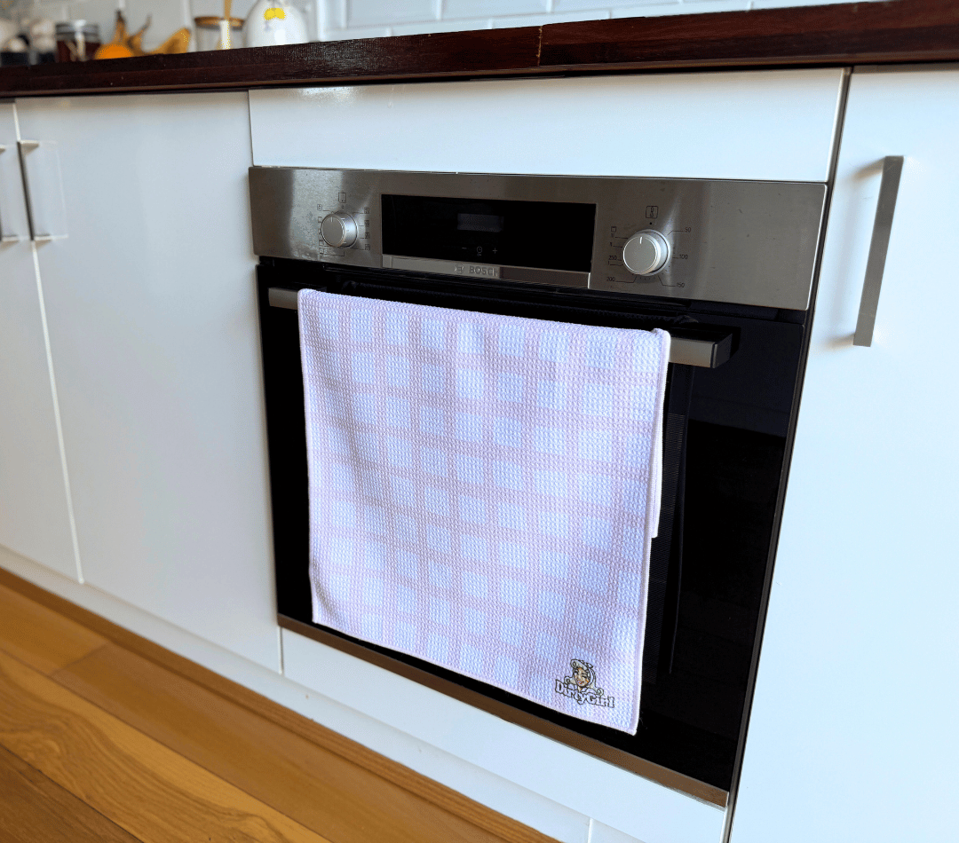 DirtyGirl Classic Pink Tea Towel folded neatly over oven handle – Machine washable