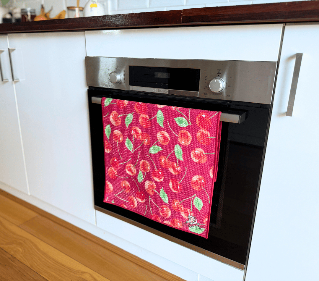 DirtyGirl Cherry Crush Tea Towel folded neatly over oven handle – Machine washable