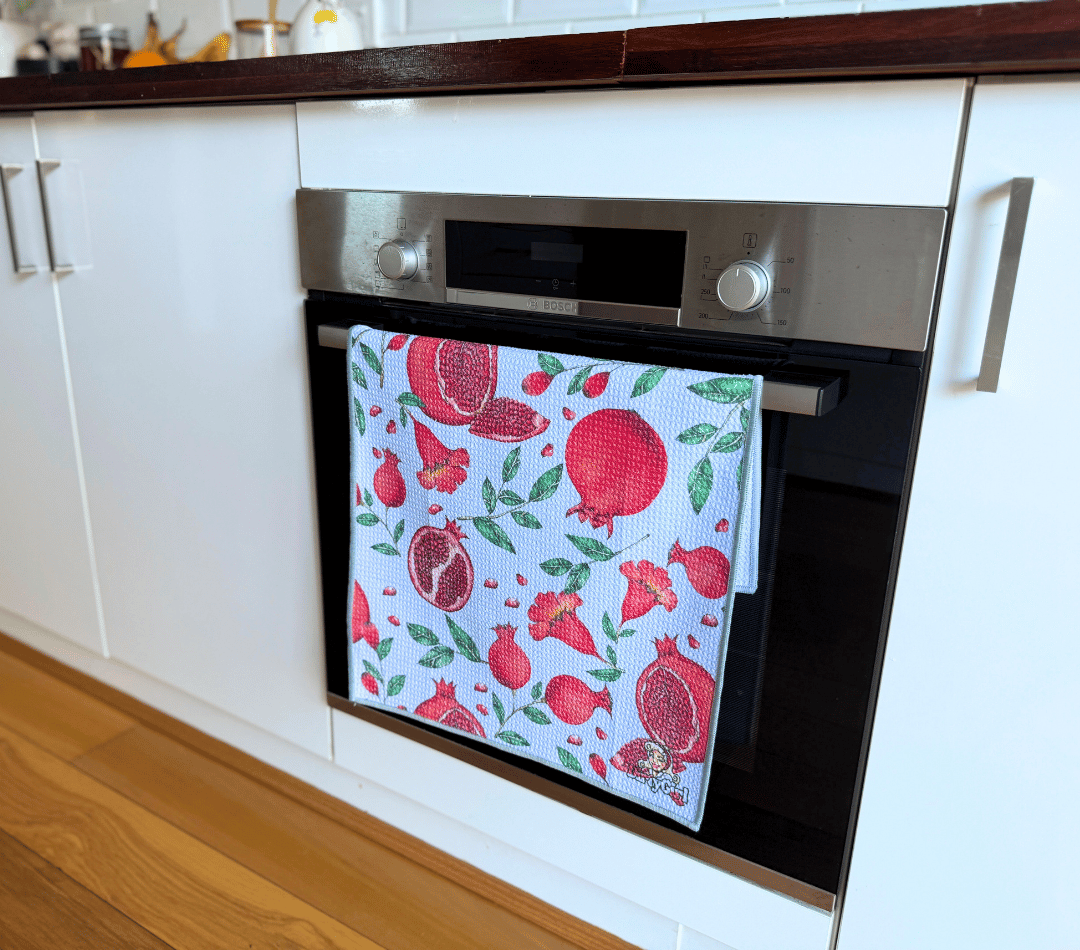 DirtyGirl Pomegranate Pop Tea Towel folded neatly over oven handle – Machine washable