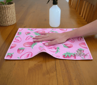 Hand wiping kitchen surface with DirtyGirl Strawberry Kiss Cloth – Lint-free finish